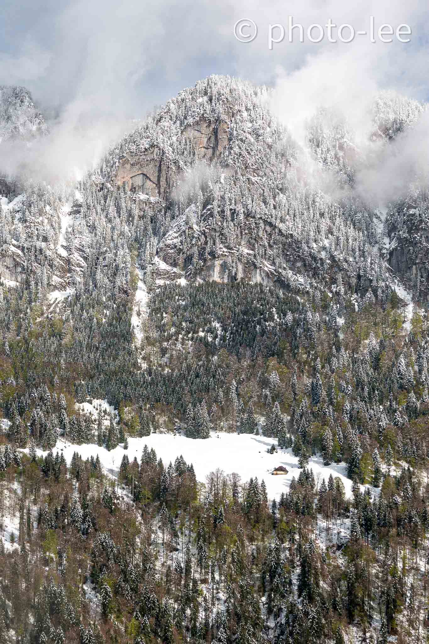 Vor einem großen Berg lieg eine einsame Hütte am Hang